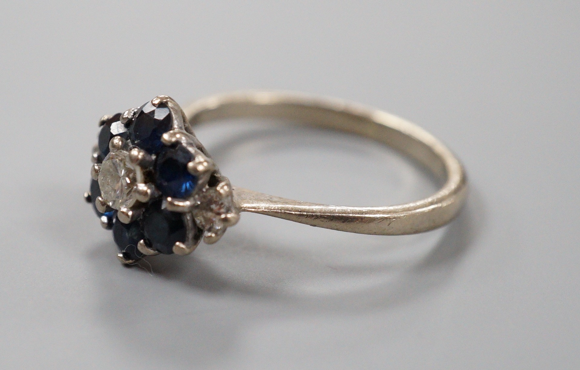 An 18ct white metal, sapphire and diamond set cluster ring, size O, gross weight 4.1 grams.